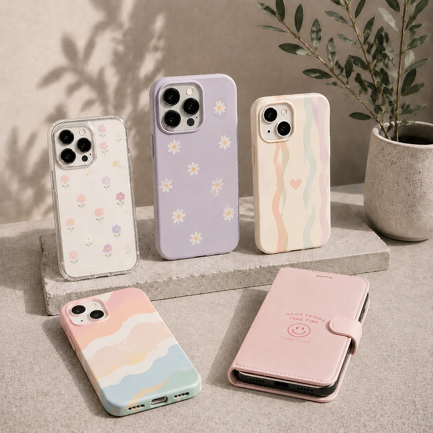 Five smartphone cases displayed on a neutral studio surface, featuring pastel floral and abstract wavy designs in soft pink, purple, beige, and multicolor tones.