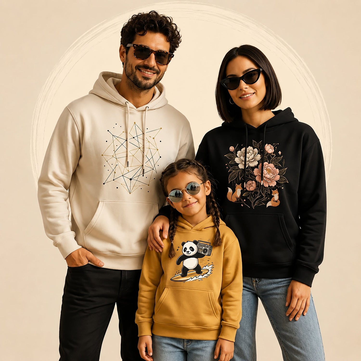 A family of three wearing hoodies with minimalist nature-inspired graphic designs, posing together in front of a clean beige studio background.